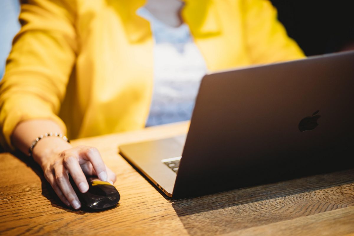 Person in yellow blazer working on laptop
